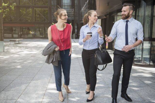 A group of colleagues laughing outside an office building during daytime